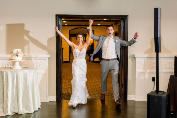 A bride and groom are holding hands in the doorway of their wedding venue.