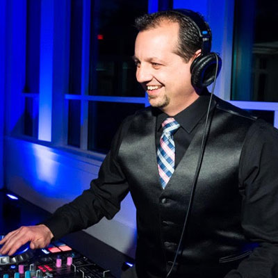 A man in black jacket and tie holding a mixer.