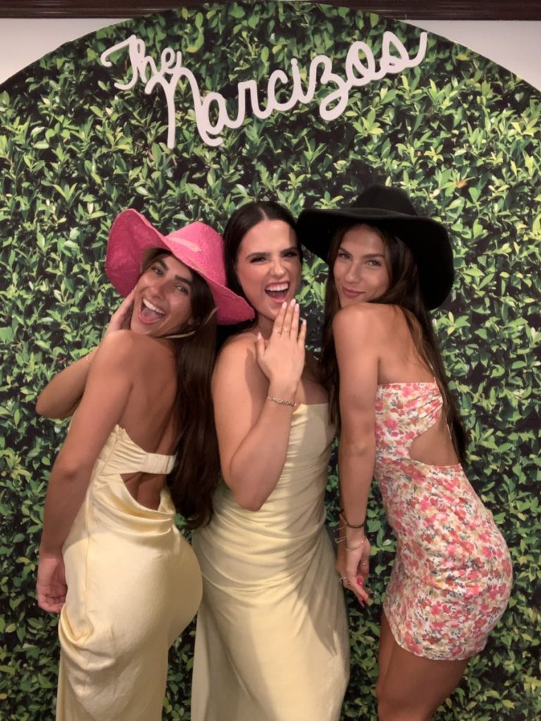 Three women posing for a picture in front of a green wall. Three women posing for a picture in front of a green wall.