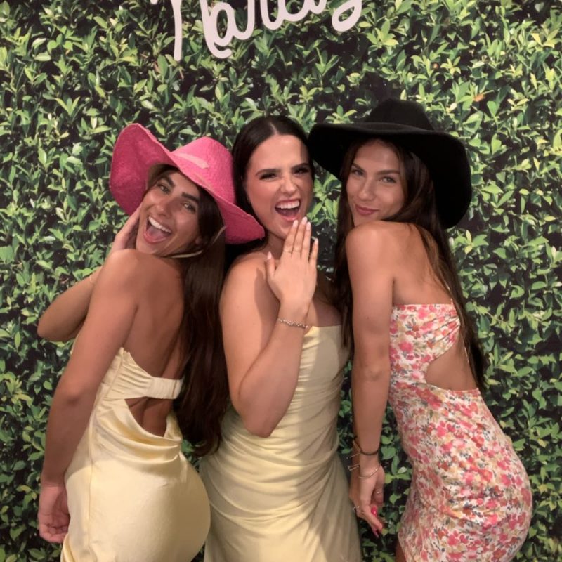 Three women posing for a picture in front of a green wall.