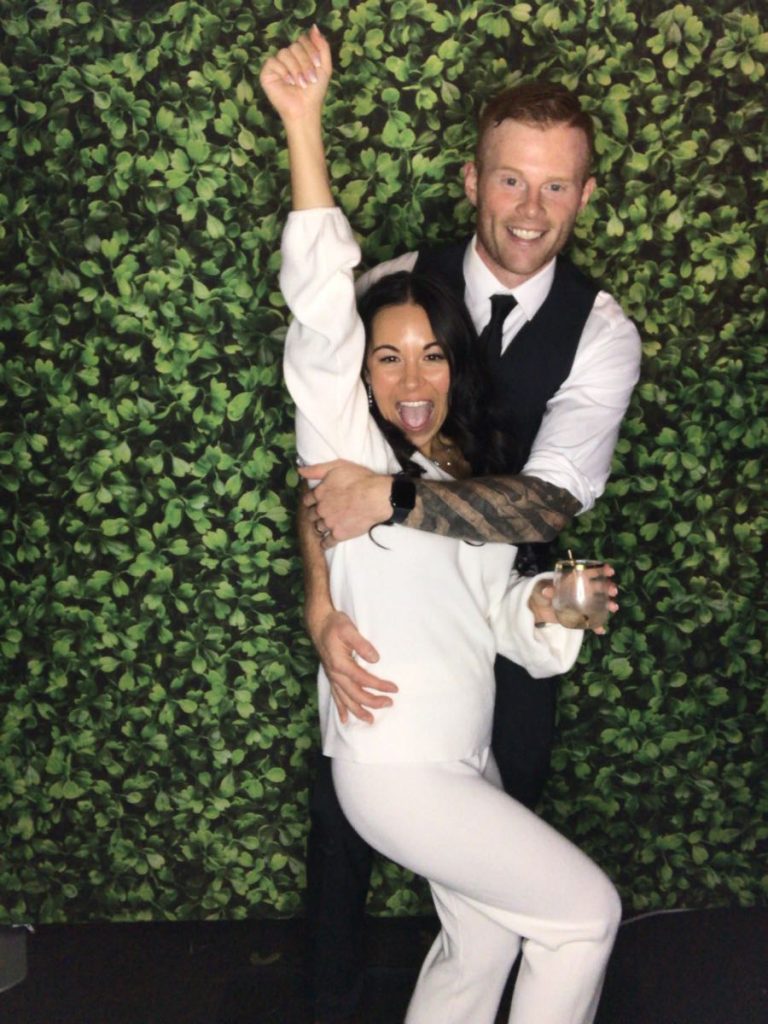 A man and woman posing for a picture in front of a wall. A man and woman posing for a picture in front of a wall.