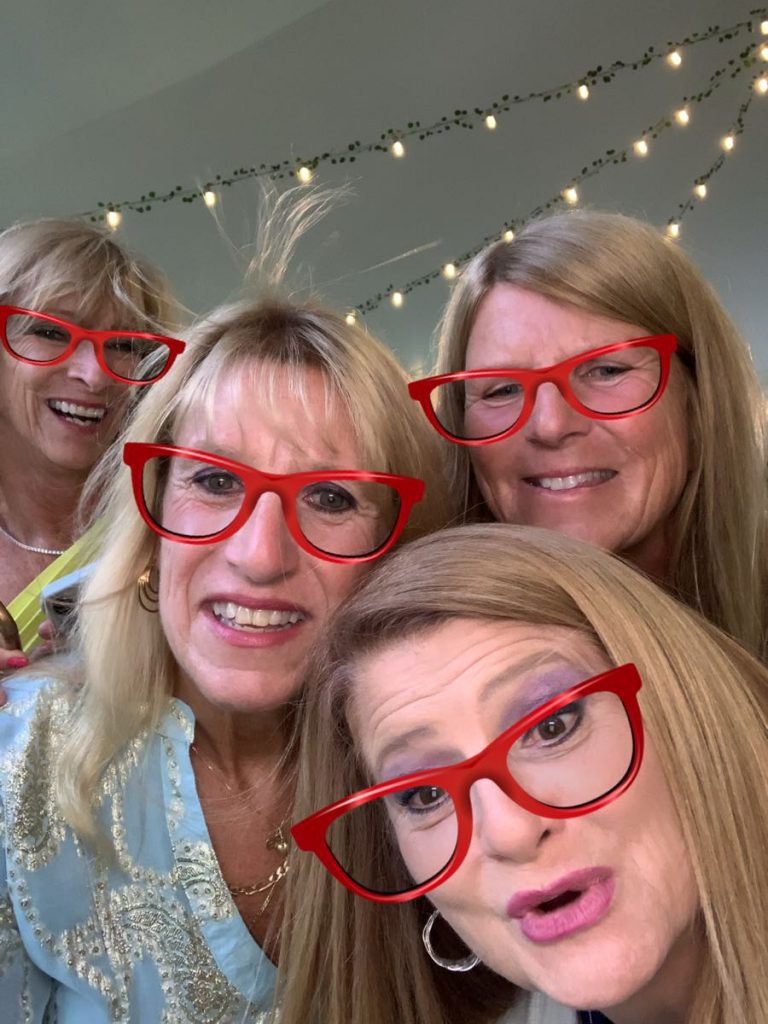 Four women wearing red glasses posing for a picture. Four women wearing red glasses posing for a picture.