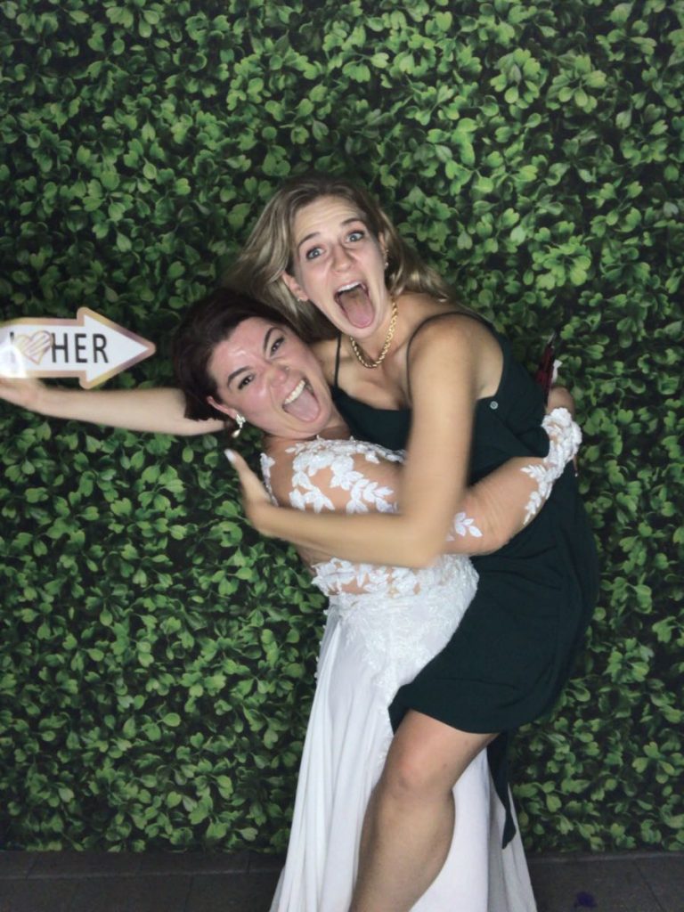 Two women posing for a photo in front of a wall. Two women posing for a photo in front of a wall.