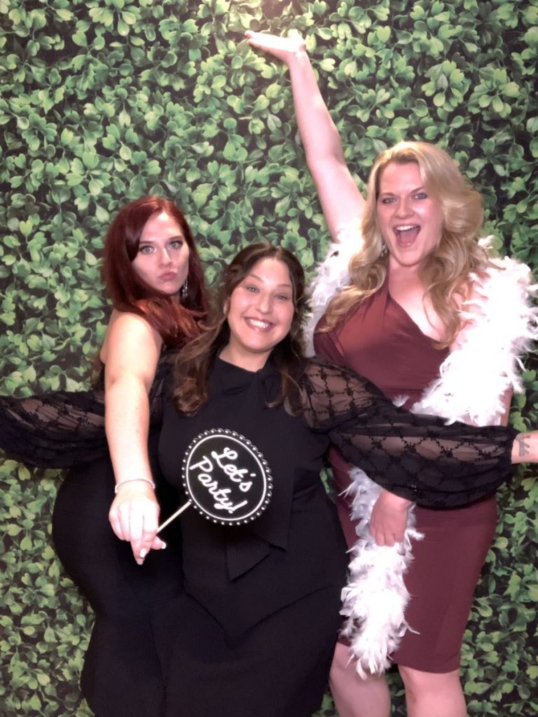 Three women posing for a photo in front of a green wall. Three women posing for a photo in front of a green wall.