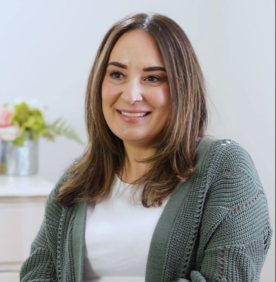 Smiling woman in a cozy green cardigan indoors.