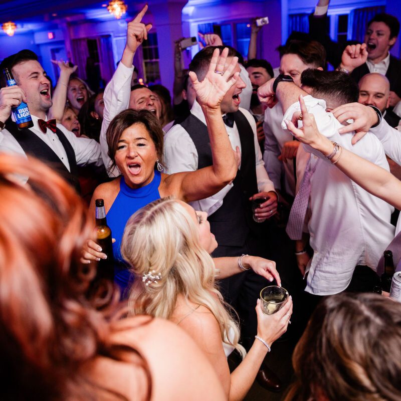 A lively crowd dancing and celebrating at a party with vibrant lighting.