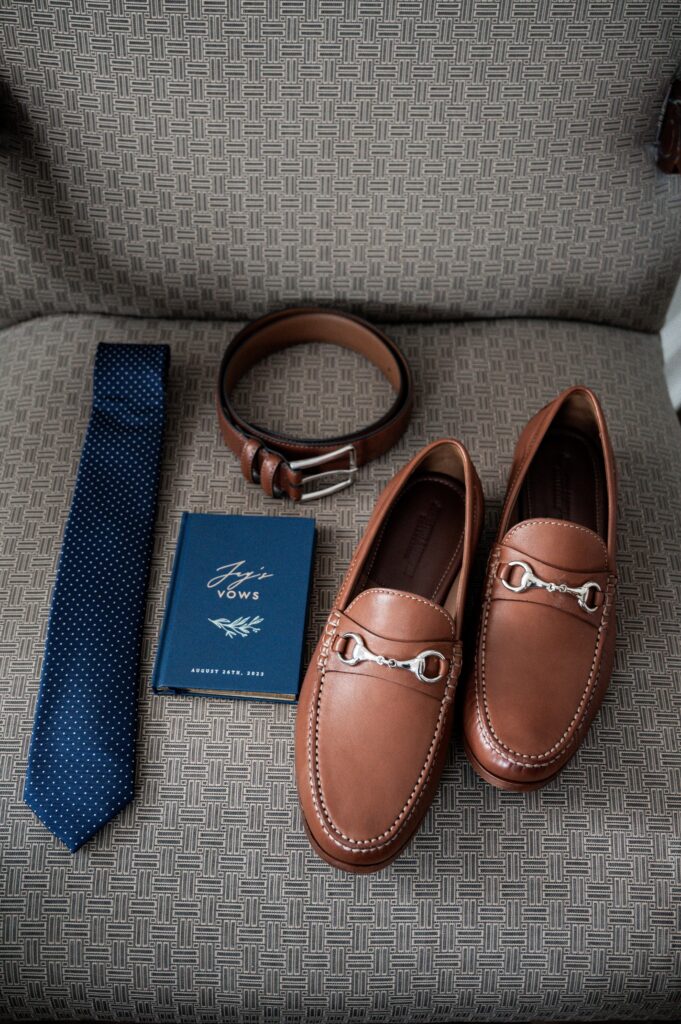 Men's accessories including loafers, a belt, tie, and a book on style. Men's accessories including loafers, a belt, tie, and a book on style.