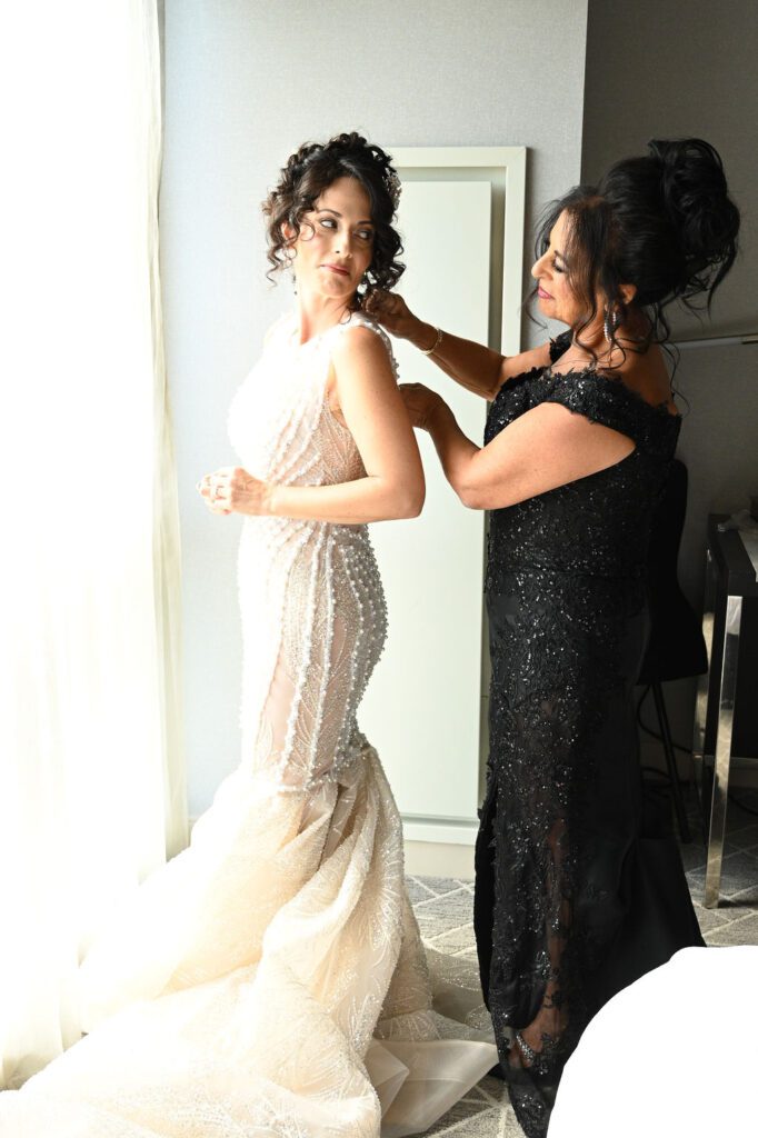 A bride getting help with her wedding dress from a woman in a black gown. A bride getting help with her wedding dress from a woman in a black gown.