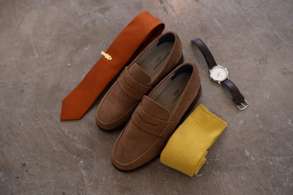 Brown loafers with a rust-colored tie and yellow pocket square. Brown loafers with a rust-colored tie and yellow pocket square.