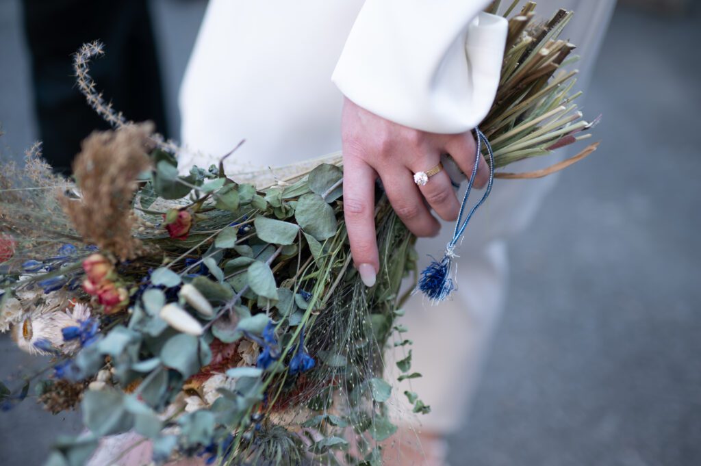 Close-up of a hand holding a rustic bouquet with dried flowers and greenery. Close-up of a hand holding a rustic bouquet with dried flowers and greenery.