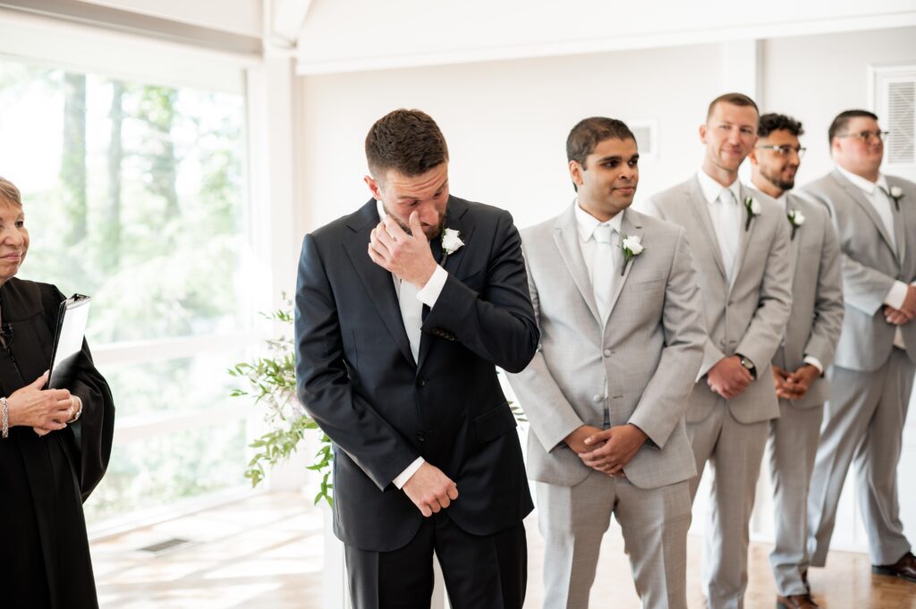 Groom wiping tears during emotional moment at wedding. Groom wiping tears during emotional moment at wedding.