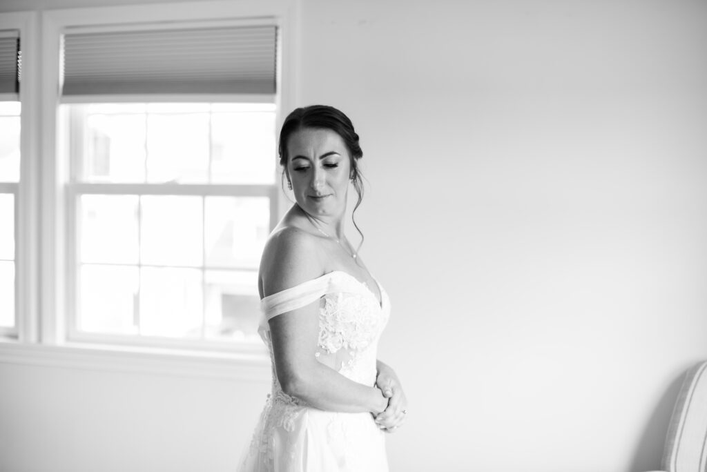 Bride in elegant white dress looking down, standing by a window. Bride in elegant white dress looking down, standing by a window.