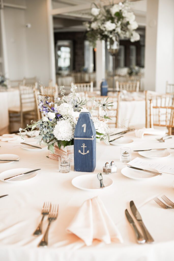 Elegant nautical-themed table setting with anchor centerpiece and floral arrangement. Elegant nautical-themed table setting with anchor centerpiece and floral arrangement.