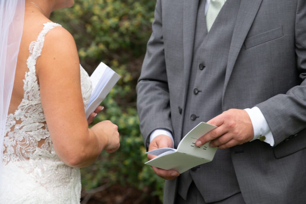 A couple exchanging wedding vows outdoors, holding papers. A couple exchanging wedding vows outdoors, holding papers.