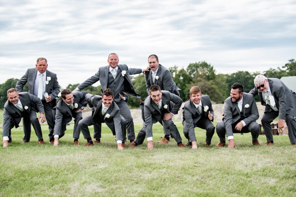 Men in tuxedos forming a human pyramid outdoors on grass. Men in tuxedos forming a human pyramid outdoors on grass.