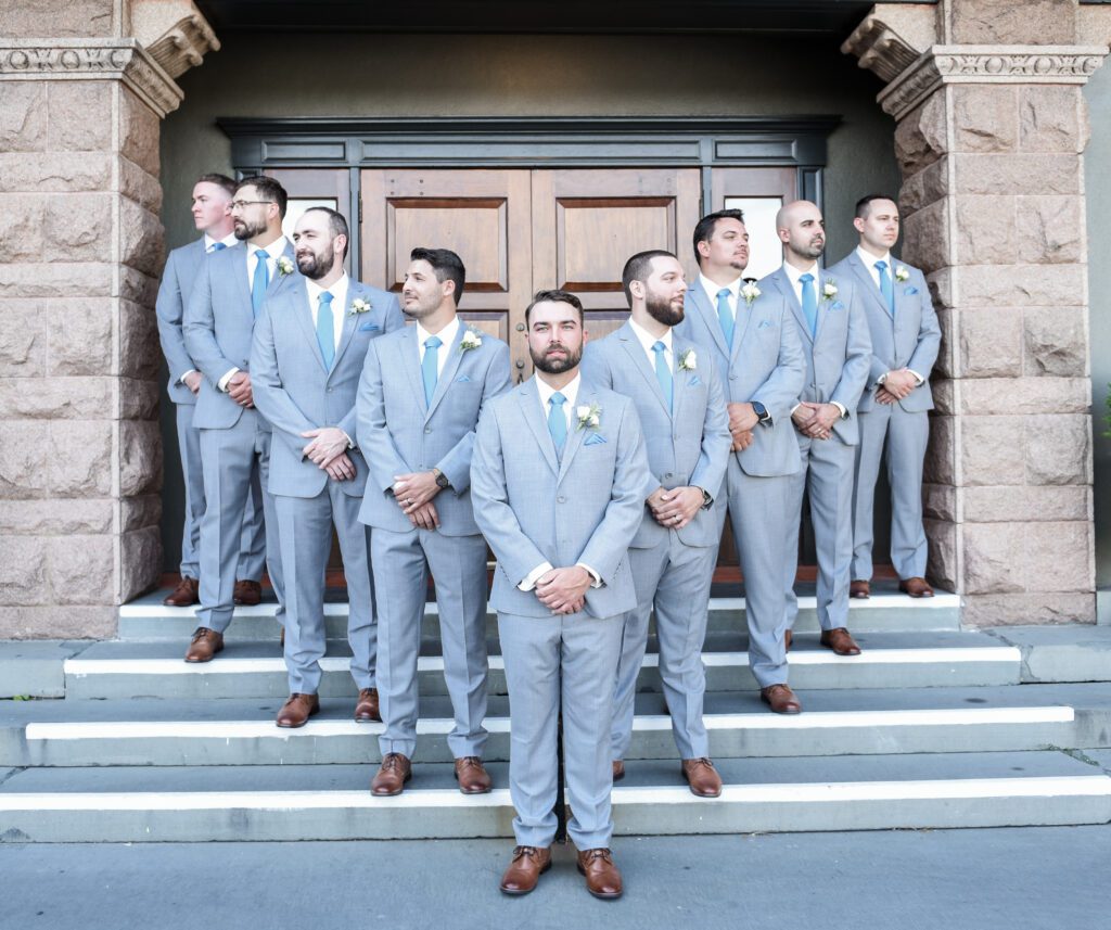 Groom and groomsmen in matching gray suits pose on church steps. Groom and groomsmen in matching gray suits pose on church steps.