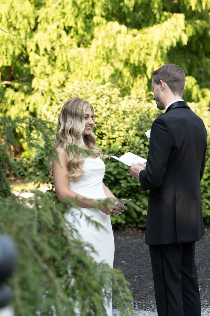 Bride and groom exchanging vows outdoors surrounded by greenery. Bride and groom exchanging vows outdoors surrounded by greenery.