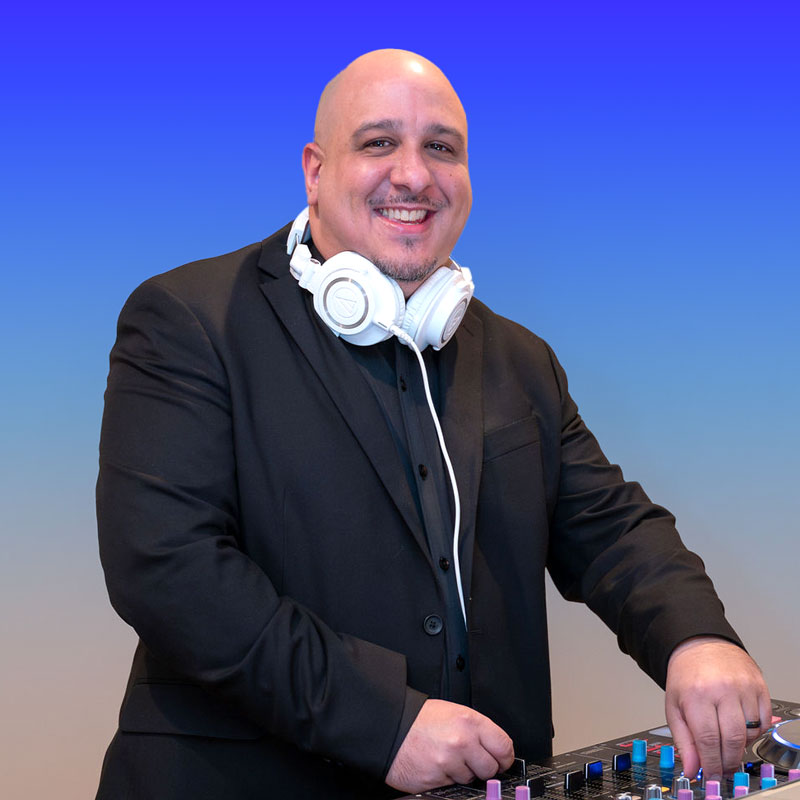 Smiling DJ in a suit with headphones at the mixing console.