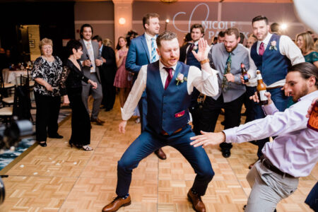 A man in blue vest and red tie standing on the floor.