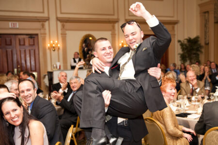 Two men in suits are holding each other up.