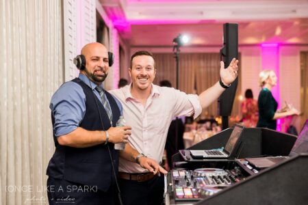 Two men are posing for a picture while holding up a speaker.