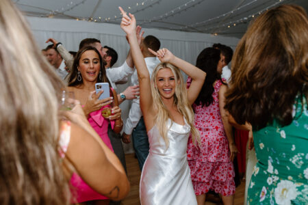 A woman in white dress holding her arms up.