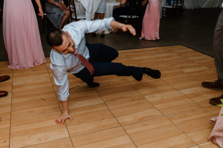 A man in white shirt and red tie on wooden floor.