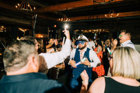 A man in a sailor 's hat and eye patch holds up his hand to the sky.
