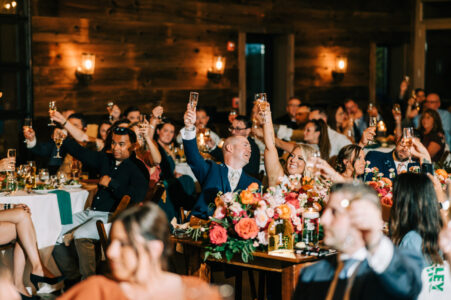 A group of people sitting at tables with their hands raised.