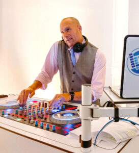 A man in a vest and tie is playing the dj mixer.