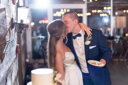 A man and woman kissing in front of a cake.