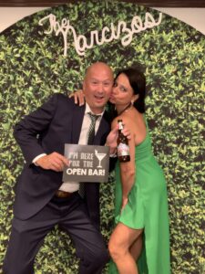 A man and woman posing for a picture in front of a green wall.