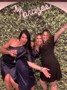 Three women posing for a picture in front of a wall.