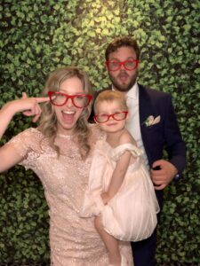 A family posing for a photo in front of a green wall.