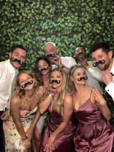 A group of people posing for a photo with fake mustaches on their faces.