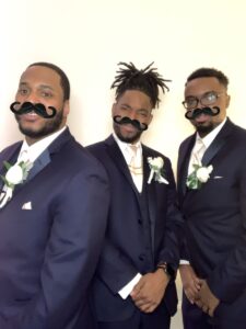 Three men in suits and ties with fake mustaches on their heads.
