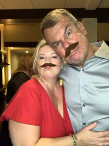 A man and woman with fake mustaches on their faces.
