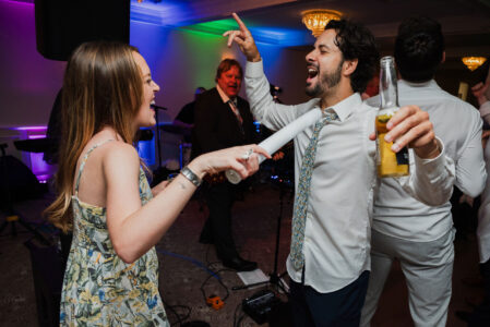 A man and woman playing wii while another holds up his hand.
