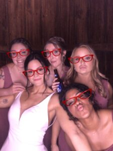 A group of women posing for a picture with red glasses on.