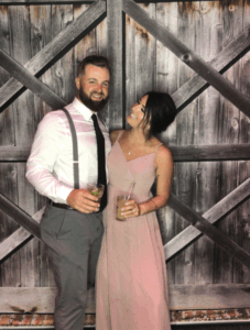 A man and woman holding drinks in front of a barn door.