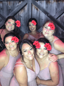 A group of women in pink dresses with red flowers on their heads.