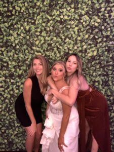 Three women posing for a photo in front of a wall.