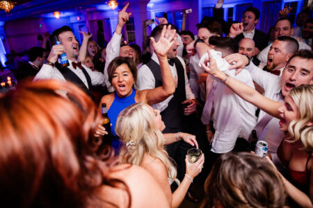 A lively crowd dancing and celebrating at a party with vibrant lighting.