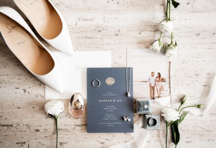 Elegant wedding invitation with rings, shoes, and flowers arranged beautifully.