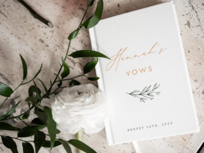 A wedding vow booklet with white flowers and greenery.