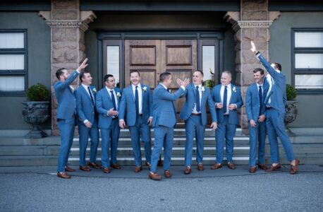 A group of men in blue suits celebrating outside a building.