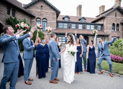 Happy wedding party celebrating outside a historic building.