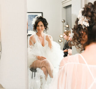 A woman in a white robe sitting and looking into a mirror.
