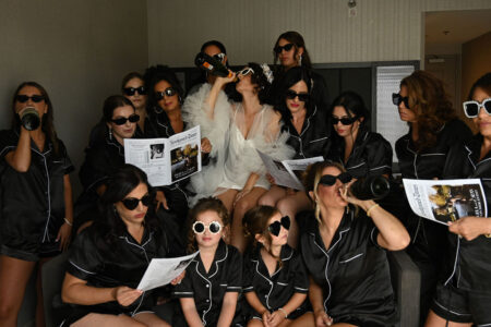 Group of women in black satin outfits and sunglasses.