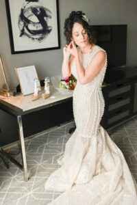 Bride in a lace wedding dress posing thoughtfully indoors.